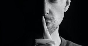 Man in the shadows with finger over lips